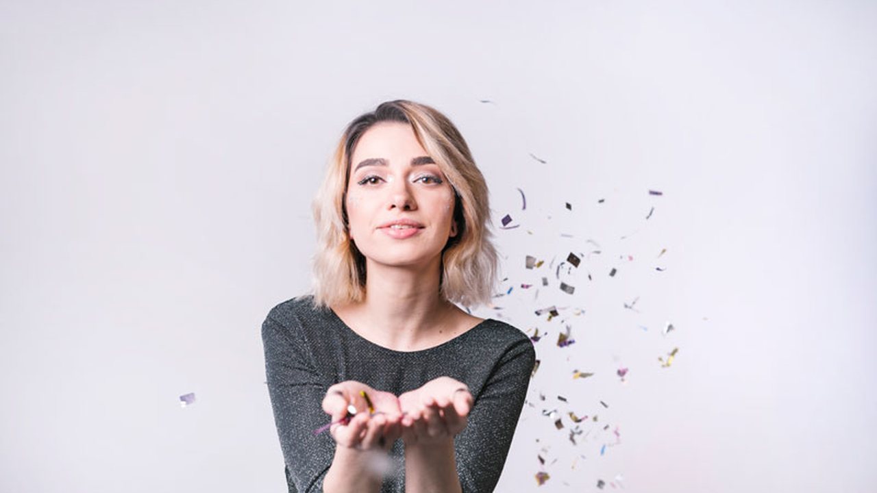 Woman blowing confetti from her hands